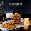 綁繩堆疊肉鬆核桃酥餅乾，旁有牛奶杯與核桃仁，背景黑色盒裝.