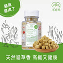 透明塑膠瓶裝貓草雞肉丁凍乾，木碟盛裝方塊狀顆粒，標籤綠白色設計.