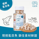 透明塑膠罐裝極鮮虱目魚凍乾方塊，旁邊木碟盛裝產品顆粒.