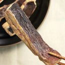 凍乾魷魚片特寫，深褐色干燥魷魚質地，筷子夾持展示細節.