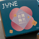 深藍色包裝盒，印有粉紅色梅花圖案與白色「JUNE 1ST.」字樣，台灣梅片標籤設計簡約雅致.
