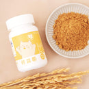 白色塑膠瓶裝犬貓保健營養粉，黃色標籤有貓咪圖案，旁邊白碟裝棕色粉末，前景有稻穗.
