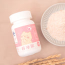白色塑膠瓶裝粉末，粉紅色標籤有卡通貓咪圖案與中文字樣，旁邊有白色盤子裝有粉狀物.