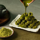 京都宇治抹茶蛋捲堆疊於白色長方盤中，抹茶醬緩緩倒淋，旁邊擺有抹茶粉瓷碟與茶壺.