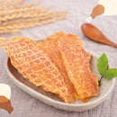 淺褐色烘乾雞肉片擺放於淺色陶瓷碟上，背景柔和布料與綠葉點綴.