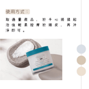 白色圓罐裝海鹽舒緩頭皮潔淨霜，藍色蓋子，旁邊放有海鹽晶粒和灰色毛巾.