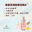 粉色透明瓶身蜂蜜亮澤柔順洗頭水，附粉色按壓式瓶蓋，背景有櫻花與蜂蜜元素.