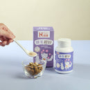 紫色包裝貓咪排毛保健品盒子及白色瓶身，旁有玻璃碗與舀取保健品的匙子.