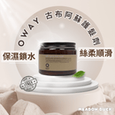 古布阿蘇護髮劑圓形深棕色罐裝，下方有綠葉裝飾，背景柔和光線.