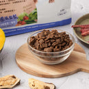 透明玻璃碗裝填小塊暗褐色狗飼料，置於圓形木質砧板上.