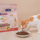 倍力SENSE貓飼料田野雞口味1.5kg，包裝粉紅色配貓咪圖案，旁有白橘色貓咪正在吃飼料.
