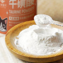 木質小碟盛裝細緻白色牛磺酸粉末，透明塑膠量匙取粉，背景橘色包裝瓶標示牛磺酸字樣.